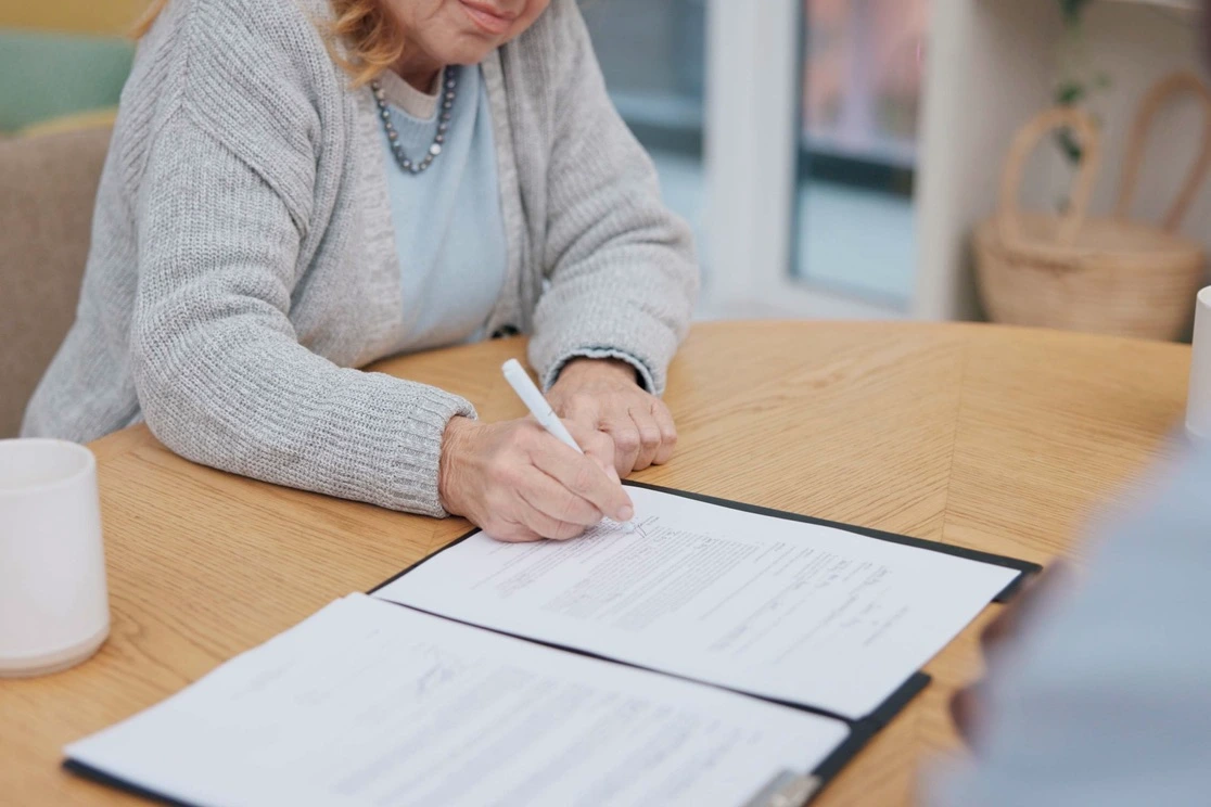 Inwonende hulp wordt geregeld via een thuiszorgorganisatie, waarbij een vrouw rustig de tijd neemt om een overeenkomst te ondertekenen